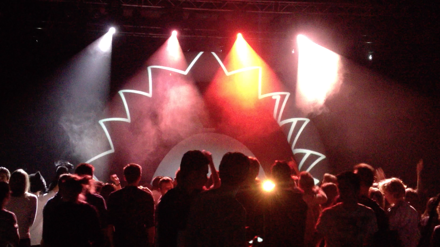 Stage projections and geometric light above a concert audience