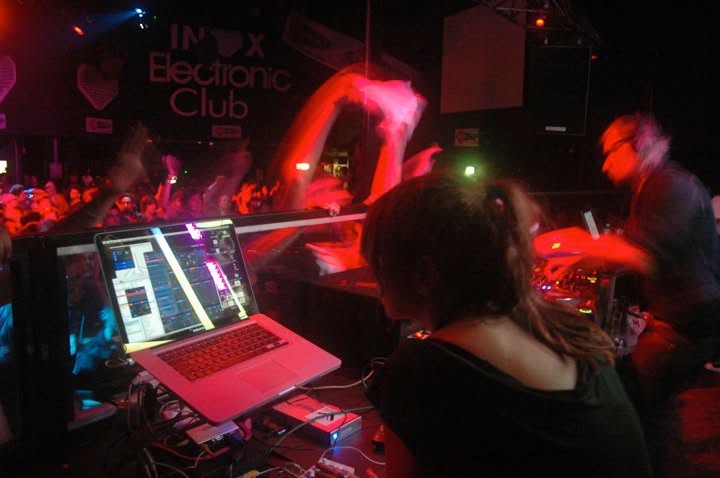 Dothy Moroders at the laptop during a club gig, with the crowd around the VJ desk
