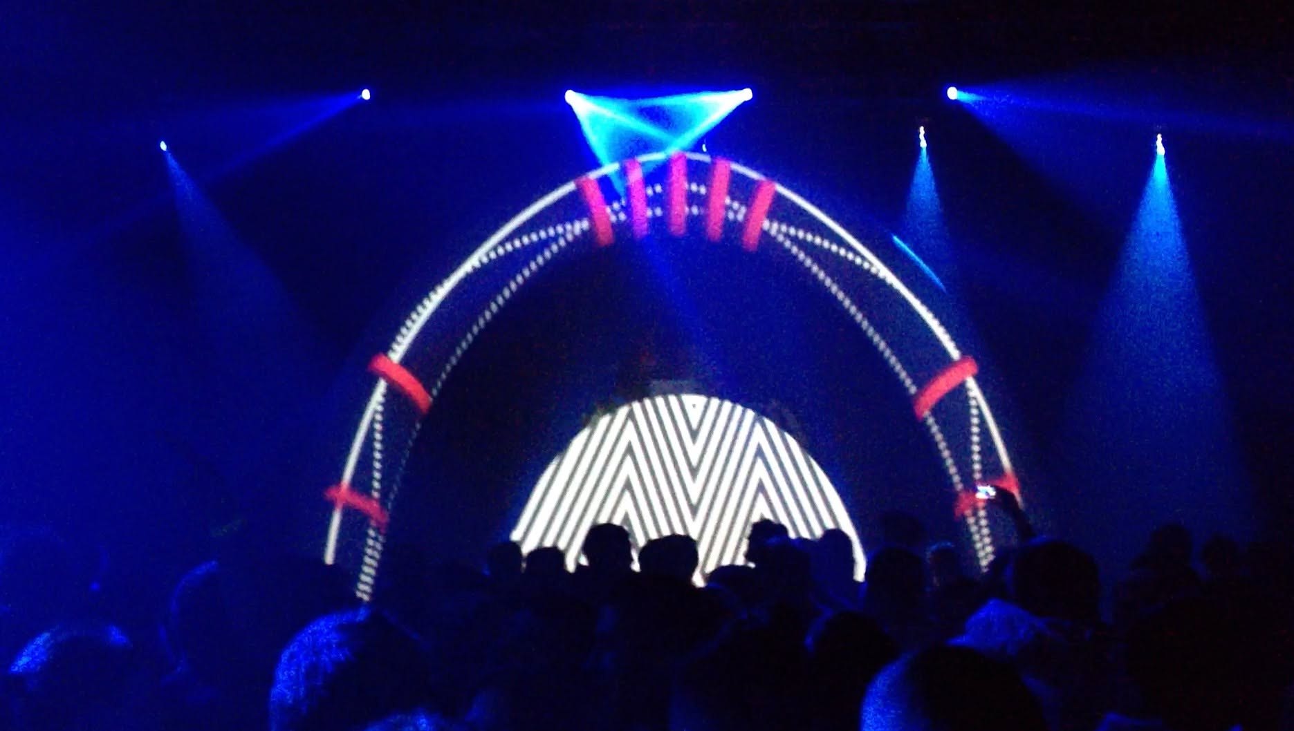 VJ live visuals: a luminous arch of light projected over a blue-lit crowd