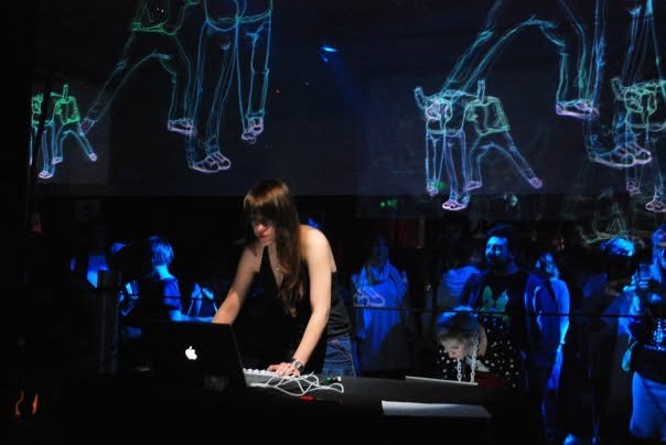 Dothy Moroders performing live visuals at a laptop in front of projected line-art animation