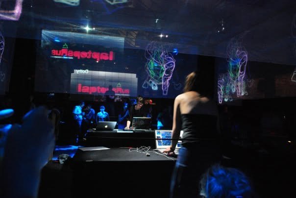 Dothy Moroders at the VJ desk in front of a large projection during a gig