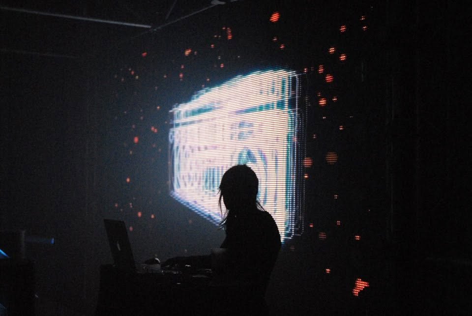 Silhouette of a VJ in front of a pixel screen in a dark club