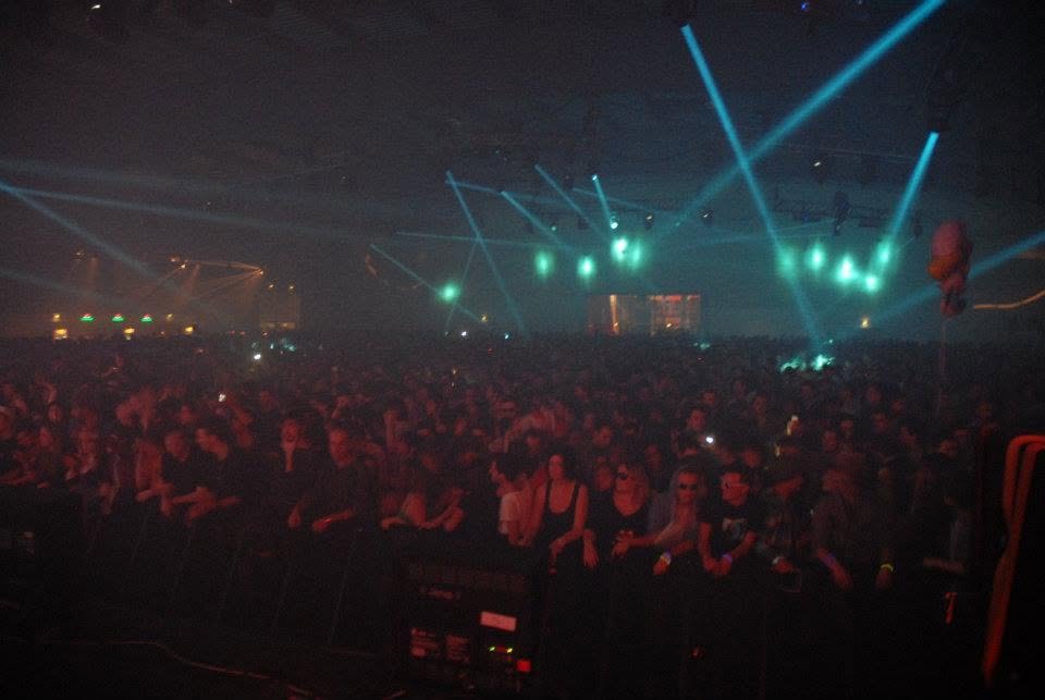 Crowd in a large venue lit by teal laser beams
