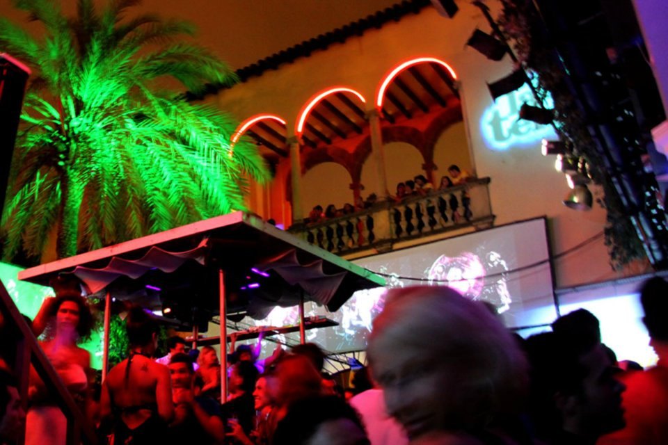 Terrace party with palm trees, arches and projections on a wall at night