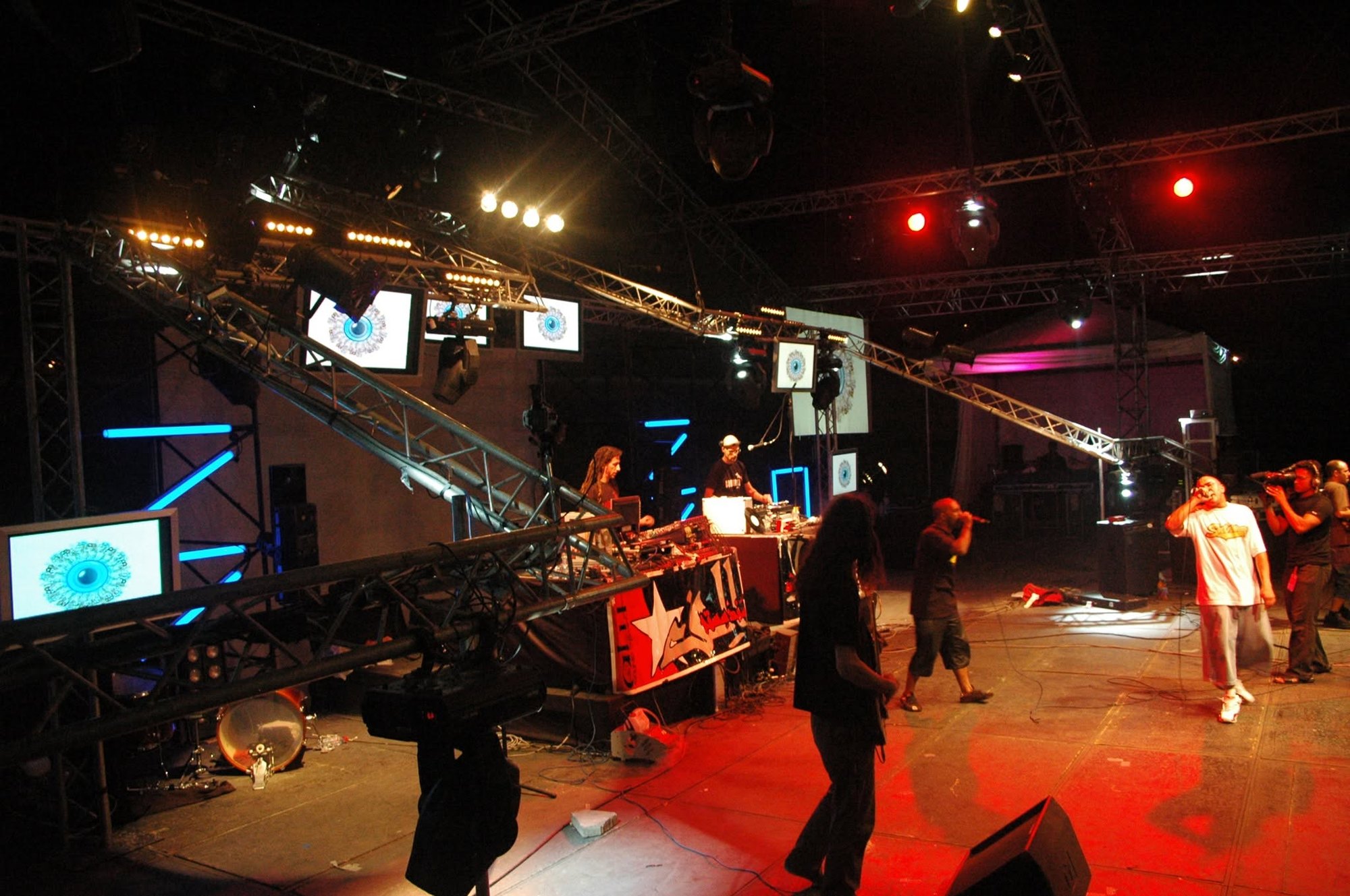 Live stage with rappers, trusses, video monitors and projected visuals in red light