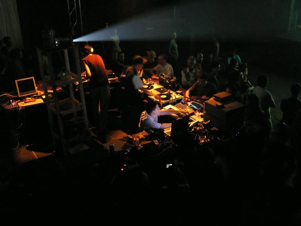 View from above of the VJ and DJ booth with the video projector beam in a dark venue