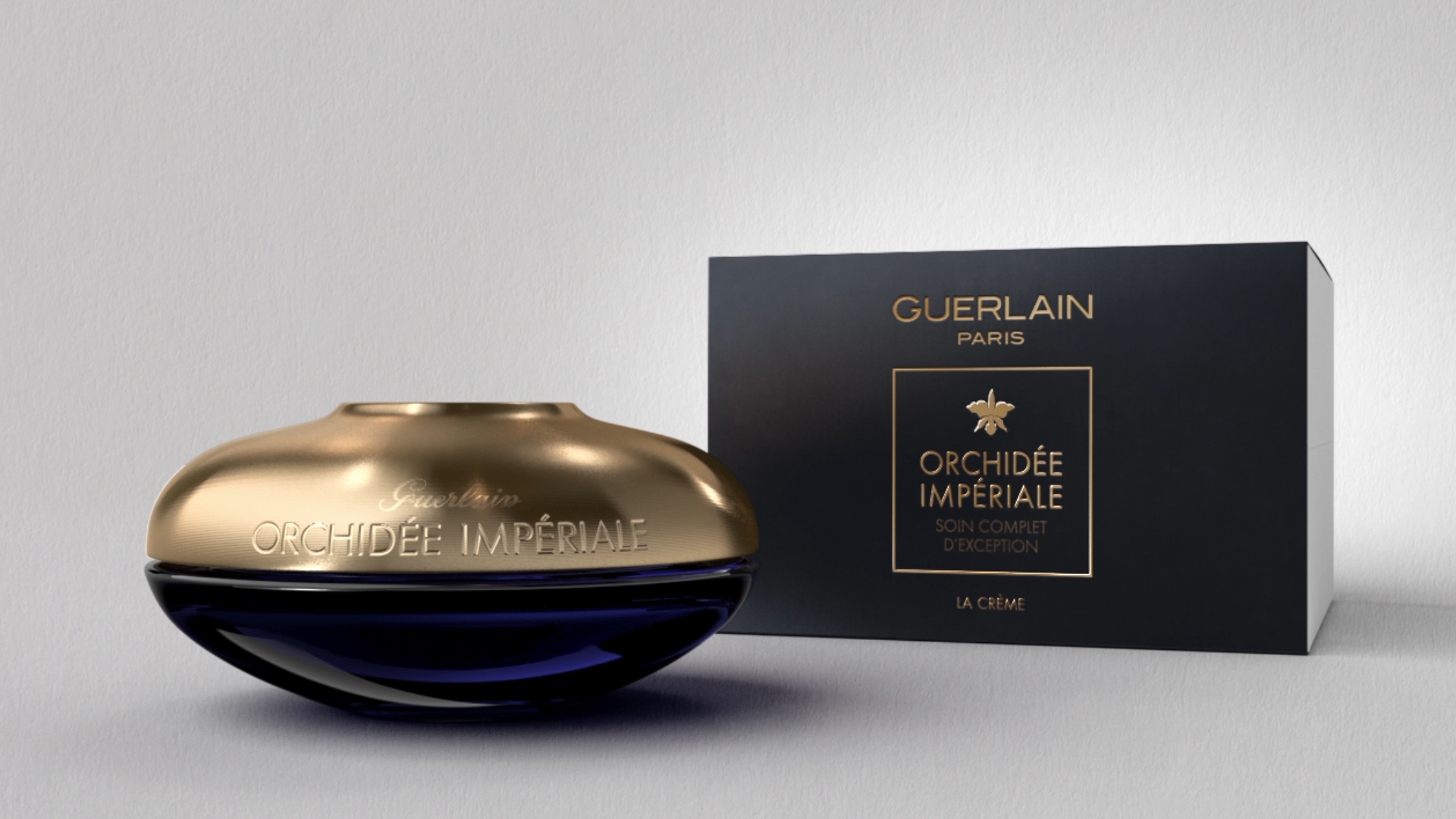 Guerlain Orchidée Impériale blue and gold jar alongside its dark presentation box
