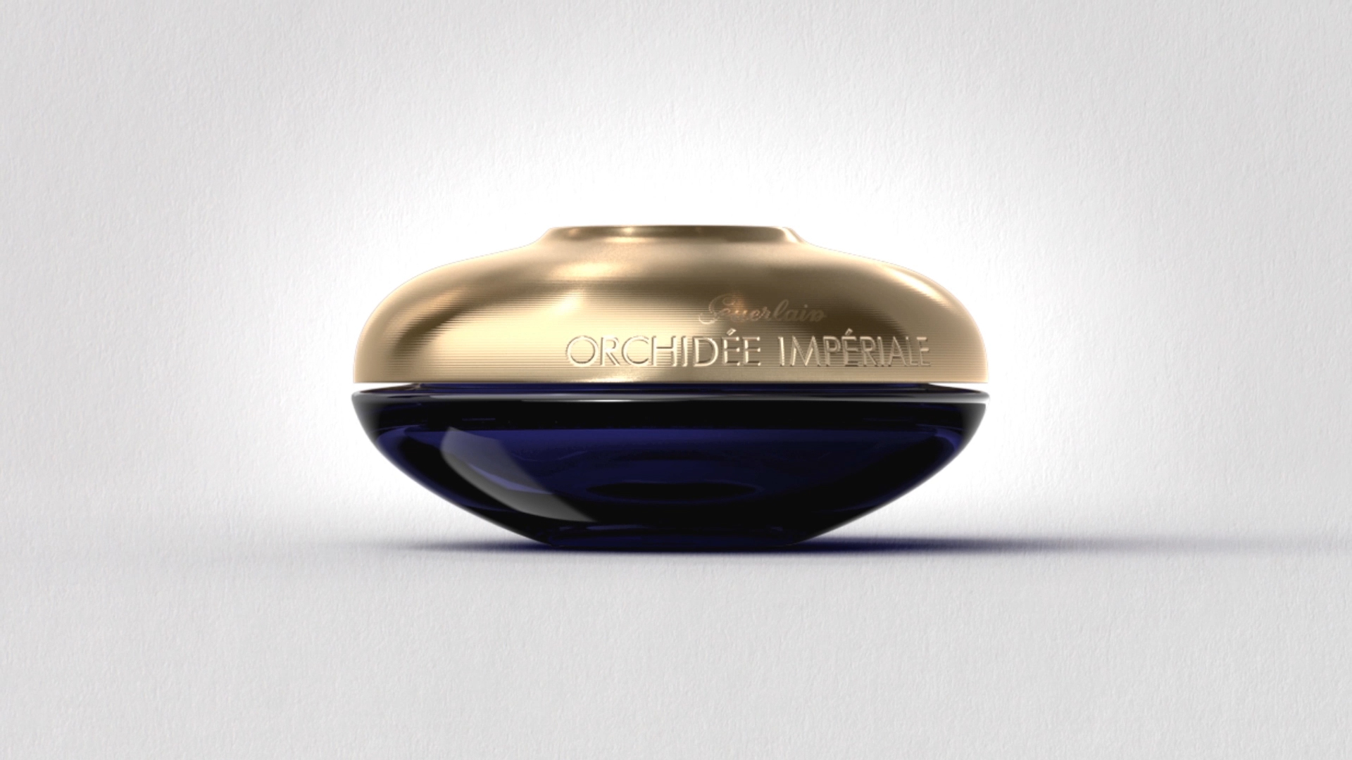 Guerlain Orchidée Impériale jar with a gold lid and deep blue glass on a light background
